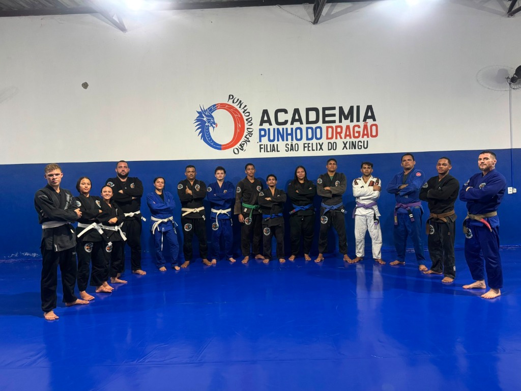 Turma adulta perfilada no tatame sob a marca da Academia Punho do Dragão